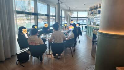 从帘子这一侧看过去，两张桌子各坐了几个人，落地窗外是水